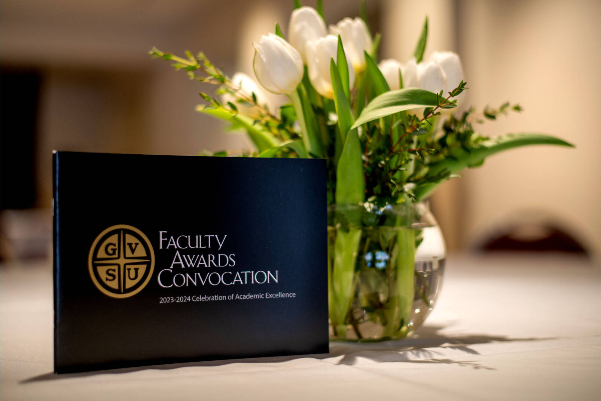Faculty Awards Convocation program on table next to small vase of flowers.